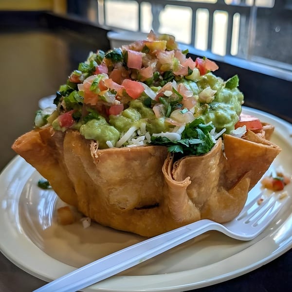 Crispy taco salad bowl filled with guacamole, pico de gallo, and shredded cheese.