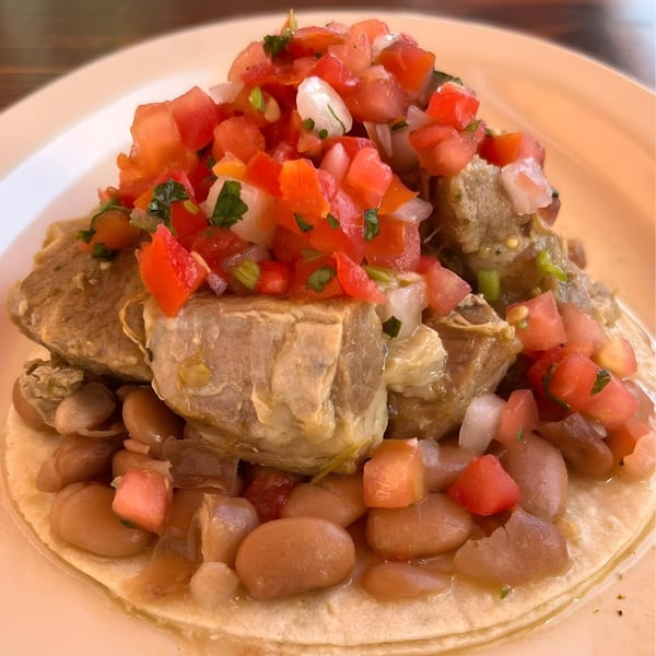 A La Corneta Taqueria taco with large pieces of meat, beans, and pico de gallo.