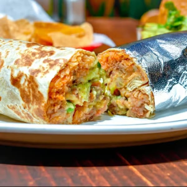 A La Corneta Taqueria burrito, cut in half, revealing rice, beans, and guacamole.